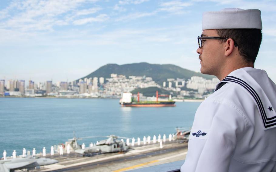 Airman Sean Farrell, from Camarillo, California, mans the rails as the U.S. Navy’s only forward-deployed aircraft carrier, USS Ronald Reagan (CVN 76), pulls in to Busan, Republic of Korea, for a routine port visit. Ronald Reagan, the flagship of Carrier Strike Group 5, provides a combat-ready force that protects and defends the United States, and supports alliances, partnerships and collective maritime interests in the Indo-Pacific region. (U.S. Navy photo by Mass Communication Specialist 3rd Gorge Cardenas