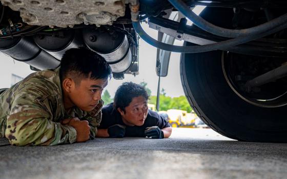 Photo Of U.S. Air Force Staff Sgt. Gabriel Pereda, 35th Logistics Readiness Squadron (LRS) Ground Transportation operator, and a LRS Ground Transportation member crawl under a wrecker to inspect its parts at Misawa Air Base, Japan, Aug. 28, 2024.