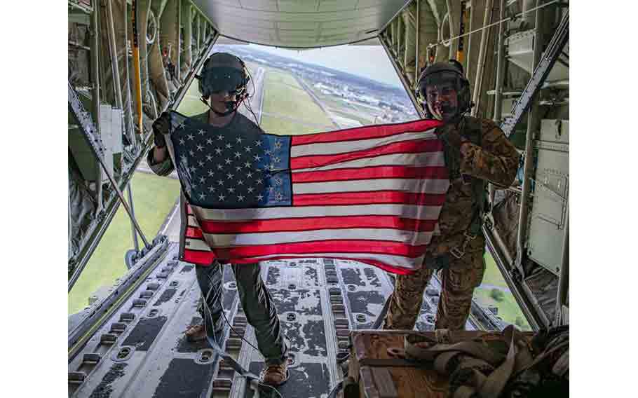 From the left, U.S. Air Force Airman 1st Class Blake Parker, a loadmaster assigned to the 36th Airlift Squadron, and Senior Airman John Shobe, an instructor loadmaster, display the American flag during the wing training day