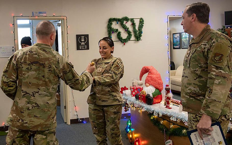 A Yokota Chiefs Group member presents a bottle of champagne to Senior Master Sgt. Danielle Hilliard, 374th Force Support Squadron Sustainment Services flight superintendent, during a chief master sergeant selection tour at Yokota Air Base, Japan, Nov. 30, 2023. The Yokota Chiefs Group accompanied base leaders as they traveled across the base to surprise and celebrate the selection of seven senior enlisted members to the rank of chief master sergeant. (U.S. Air Force photo by Senior Airman Hannah Bean)