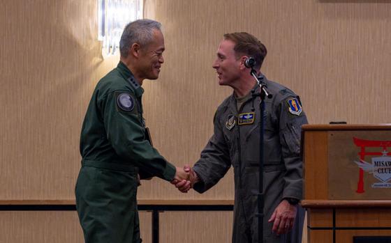 U.S. Air Force Col. Paul Davidson, right, 35th Fighter Wing commander, shakes hands with Japan Air Self-Defense Force (JASDF) Lt. Gen. Hiroshi Kameoka, Northern Air Defense Force commander, during an all-call at Misawa Air Base, Japan.
