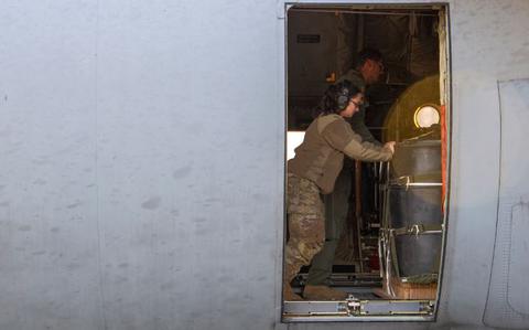 Photo Of U.S. Air Force Airman 1st Class Danielle Sugrue, 374th Logistics Readiness Squadron combat mobility flight technician and Airman 1st class Ryan Gaskins, 36th Airlift Squadron loadmaster, push a container delivery system bundle onto a C-130J Super Hercules in preparation of a night time sortie.