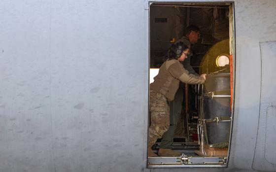 Photo Of U.S. Air Force Airman 1st Class Danielle Sugrue, 374th Logistics Readiness Squadron combat mobility flight technician and Airman 1st class Ryan Gaskins, 36th Airlift Squadron loadmaster, push a container delivery system bundle onto a C-130J Super Hercules in preparation of a night time sortie.