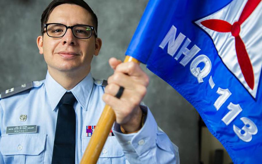 U.S. Air Force Tech. Sgt. Jeffrey MacHott, Misawa Civil Air Patrol (CAP) member, holds the CAP guidon at Misawa Air Base, Japan, Nov. 15, 2022. MacHott joined the CAP Geospatial Team that allows individuals to remotely provide damage assessment services for emergency management agencies. (U.S. Air Force photo by Tech. Sgt. Jao’Torey Johnson)