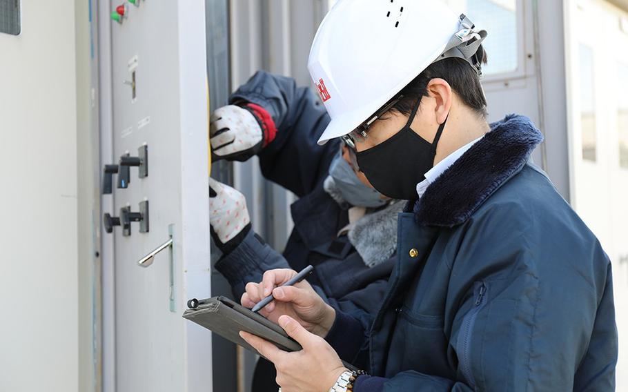 Shunsuke Nakachi, an engineer technician for U.S. Army Garrison Japan’s Directorate of Public Works Sagami Sub-Facilities Engineer, records the status of a high-voltage switcher while another employee checks it March 7 on Sagami General Depot, Japan. Nakachi and his team maintain and control utilities on the depot such as electricity, water, sewage and air conditioning. (Noriko Kudo)