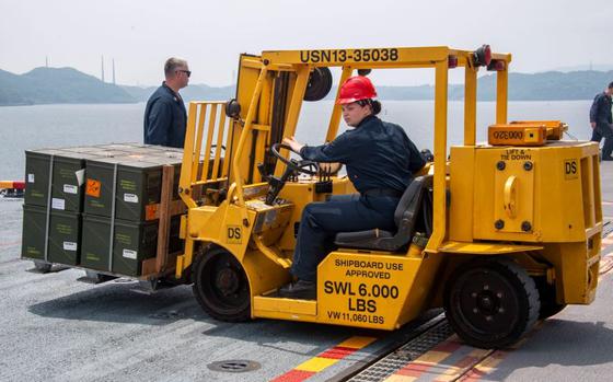 Photo Of Aviation Ordnanceman 2nd Class Michelle Tucker, from Splendora, Texas, assigned to the forward-deployed amphibious assault carrier USS America (LHA 6), operates a forklift to guide ordnance during an ammunition handling evolution in Sasebo bay June 11.