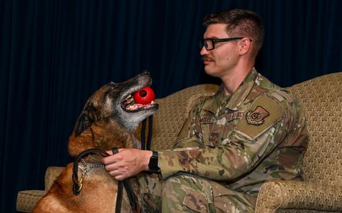 Photo Of U.S. Air Force Staff Sgt. Ian McGee, 374th Security Forces Squadron military working dog handler, and MWD Edy, sit on stage during Edy’s retirement ceremony at Yokota Air Base, Japan.