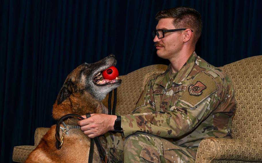U.S. Air Force Staff Sgt. Ian McGee, 374th Security Forces Squadron military working dog handler, and MWD Edy, sit on stage during Edy’s retirement ceremony at Yokota Air Base, Japan.