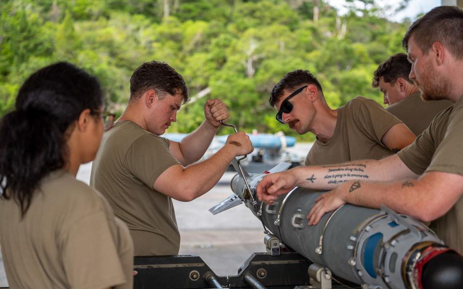 U.S. Air Force Airman Aiden Smith, left, 18th Munitions Squadron conventional maintenance technician, tightens a cover strap from a joint direct attack munition guidance tail kit on an inert GBU-31 during bomb building training.