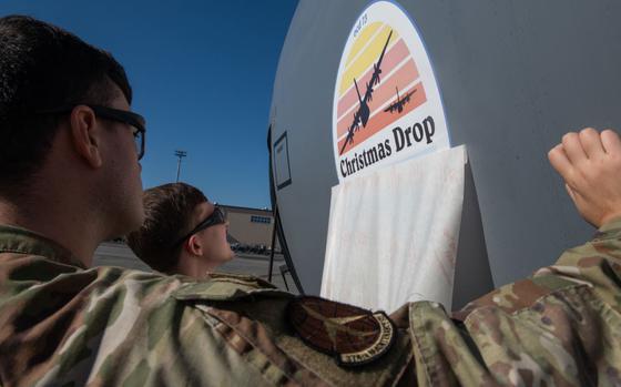 Photo Of U.S. Air Force Airman 1st Class Jacob Toney, left, and Staff Sgt. Donovan Lamore, 374th Aircraft Maintenance Squadron aircraft structural technicians, reveal the Operation Christmas Drop emblem at Yokota Air Base, Japan, Dec. 3, 2024.