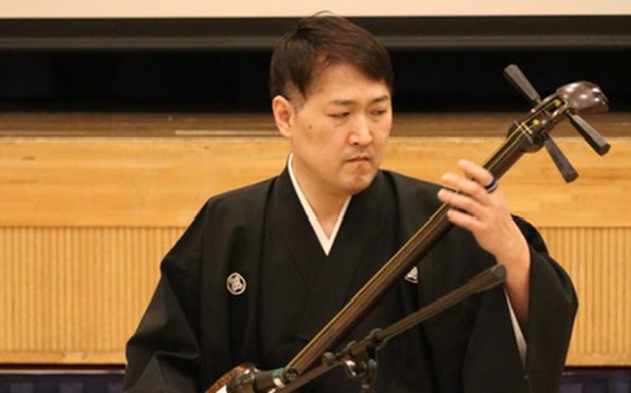 A Japanese man playing traditional Japanese instrument shamisen.