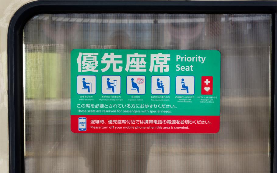 Close-up of green and red information sticker for priority seats outside of train at City of Japan on a winter day.