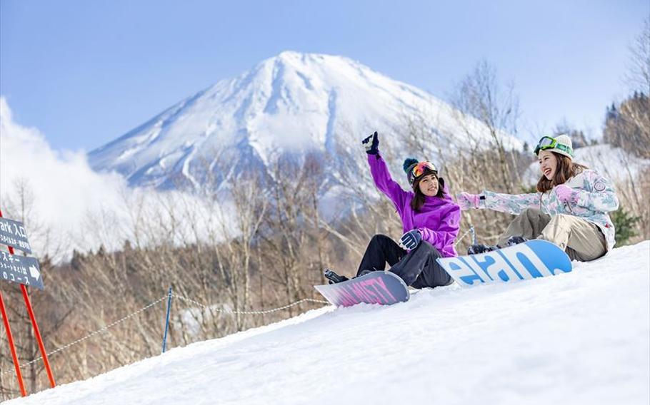 two women with snowboard sitting on the slope